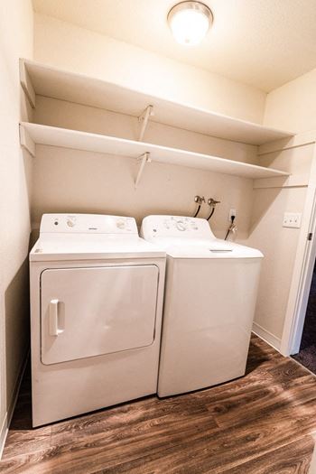 a washer and dryer in a small room with a shelf above it